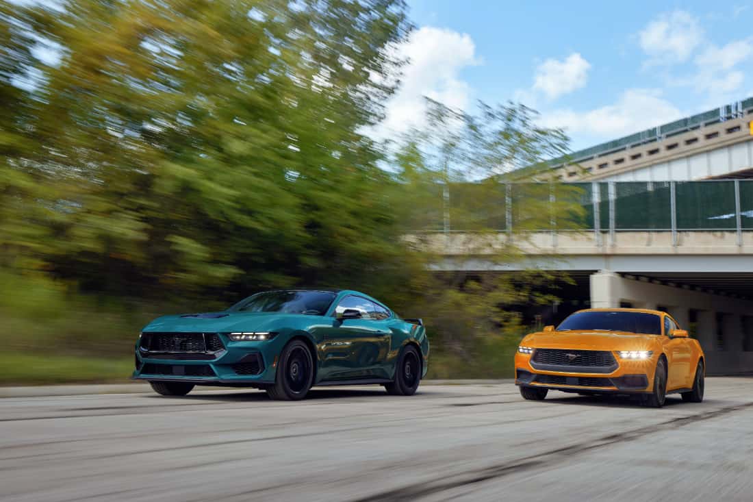 Two 2026 Ford Mustangs in teal and orange parked side by side