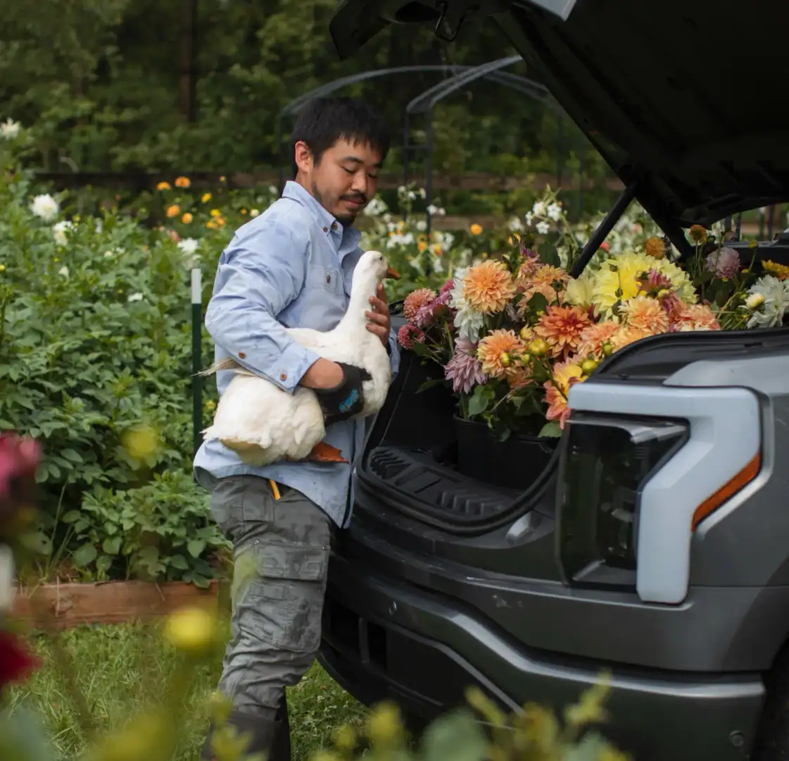 Man Standing at a F-150 Lightning Frunk holding a duck