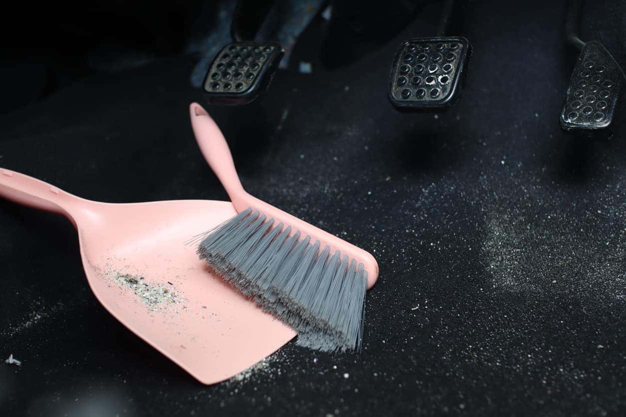A dust bin being used for cleaning the floor mats below the pedals.