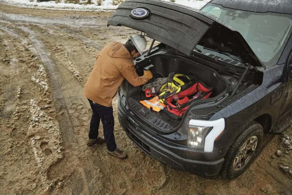 A worker grabs equipment from the front cargo area of their 2025 Ford F-150 Lightning.