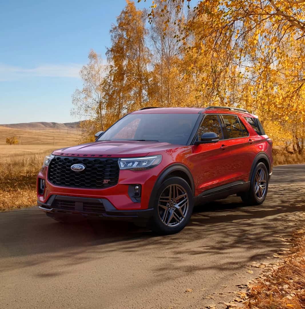 A red 2026 For d Explorer drives on an Autumn road.