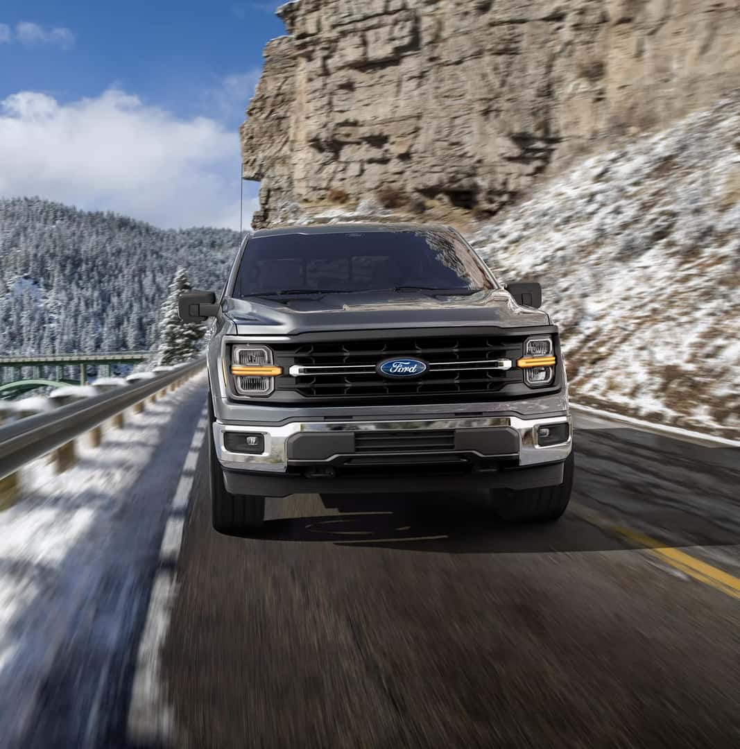 A Ford F-150 driving on a snowy road.