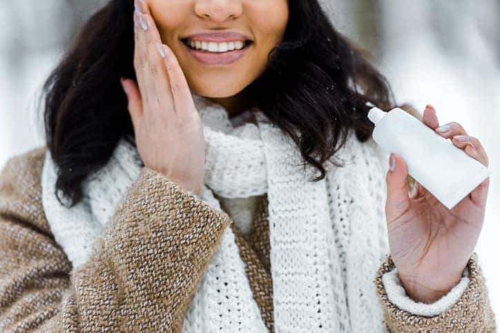 african american woman touching cheek and applying protective cream