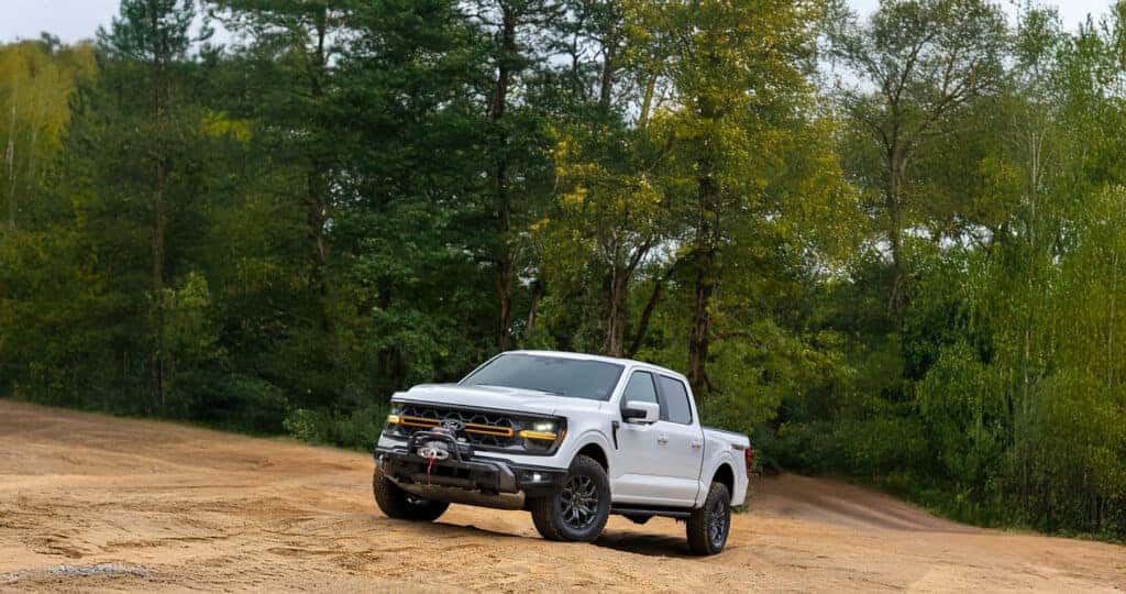 2024 Ford F-150 Tremor parked in a dirt clearing in front of green trees