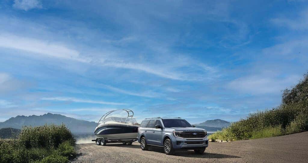 2025 Ford Expedition backing a large ski boat into a mountain lake on summer day