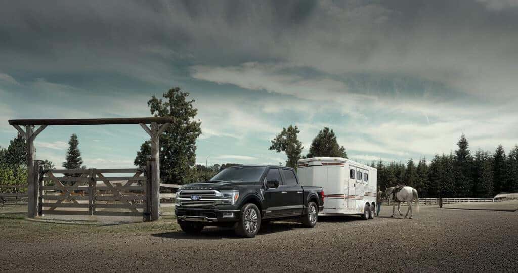2025 Ford F-150 platinum in Black towing horse trailer with a cowboy and horse unloading at ranch