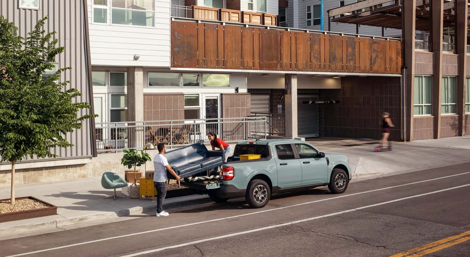 Two people unloading a couch out of the bed of the 2025 Ford Maverick XLT