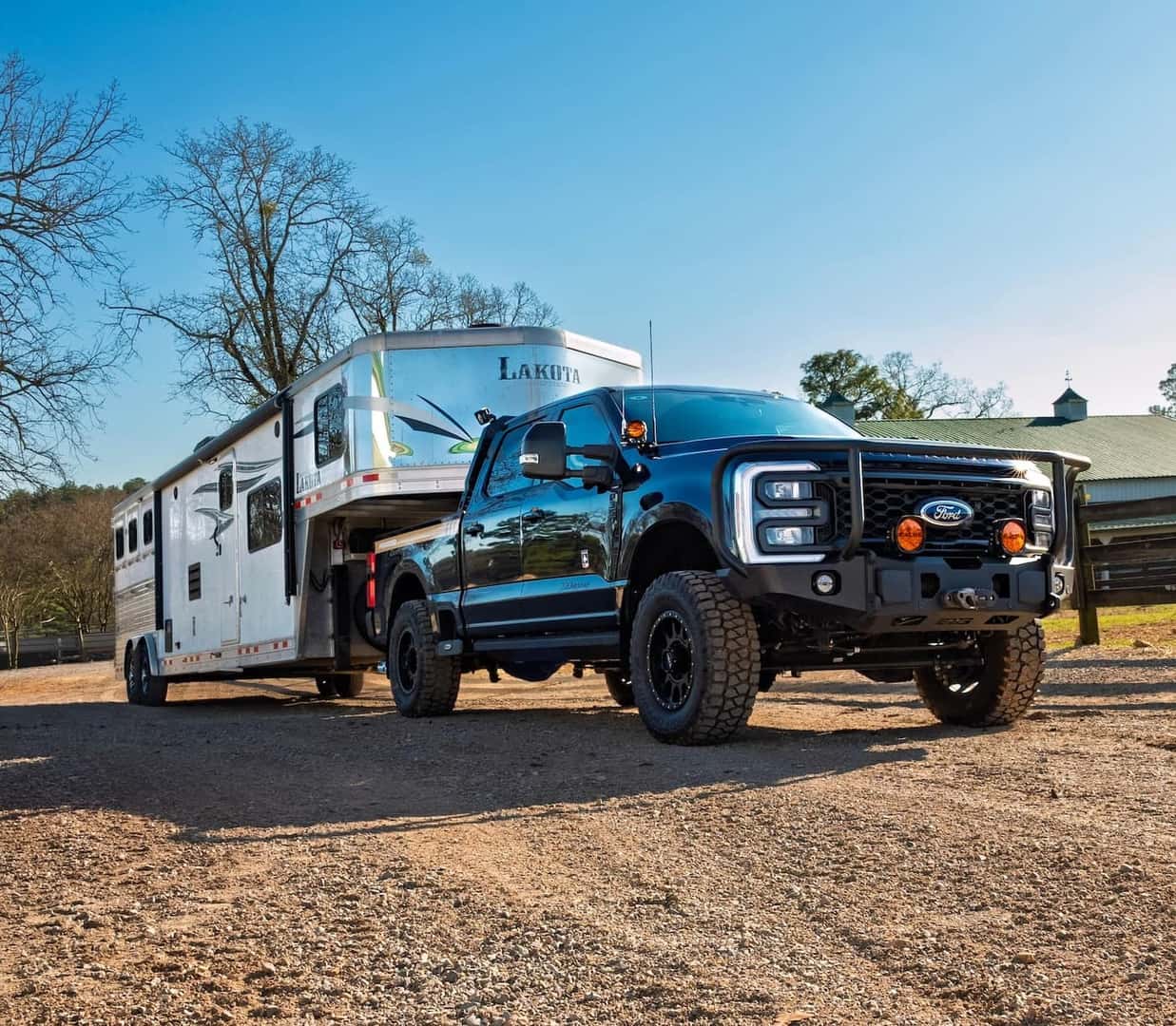 Blue 2026 Ford AGwagon Super Duty towing a Lakota horse trailer at a ranch.