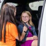 Women buckling in child in the back of vehicle