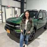 woman standing in front of a green 2025 Ford Bronco Sport