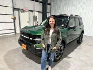 woman standing in front of a green 2025 Ford Bronco Sport