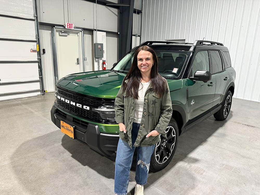 woman standing in front of a green 2025 Ford Bronco Sport