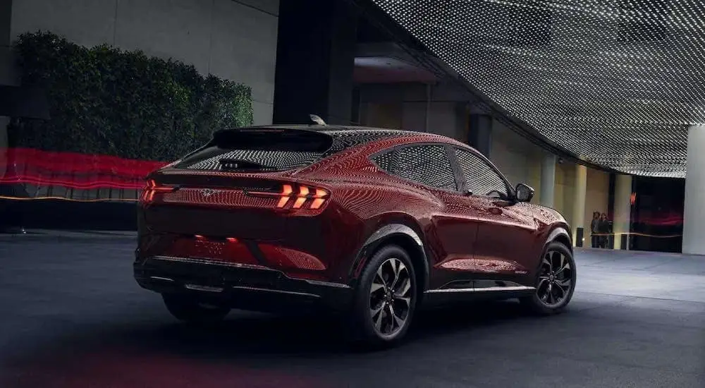 The latest Ford Mustang Mach-E for sale, a red 2024 Ford Mustang Mach-E, is shown driving in a garage.