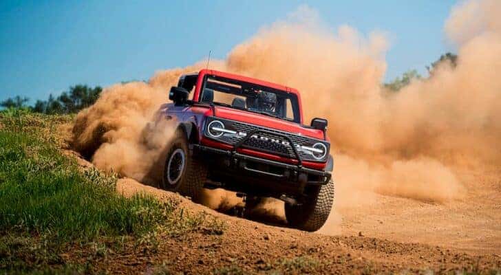 A red 2021 Ford Bronco Wildtrak is shown from the front while off-road.