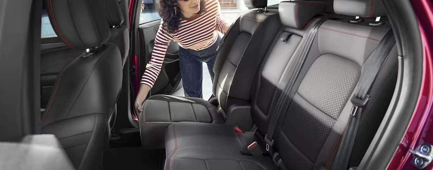 A woman is shown adjusting the rear row of seating in a red 2024 Ford Escape.