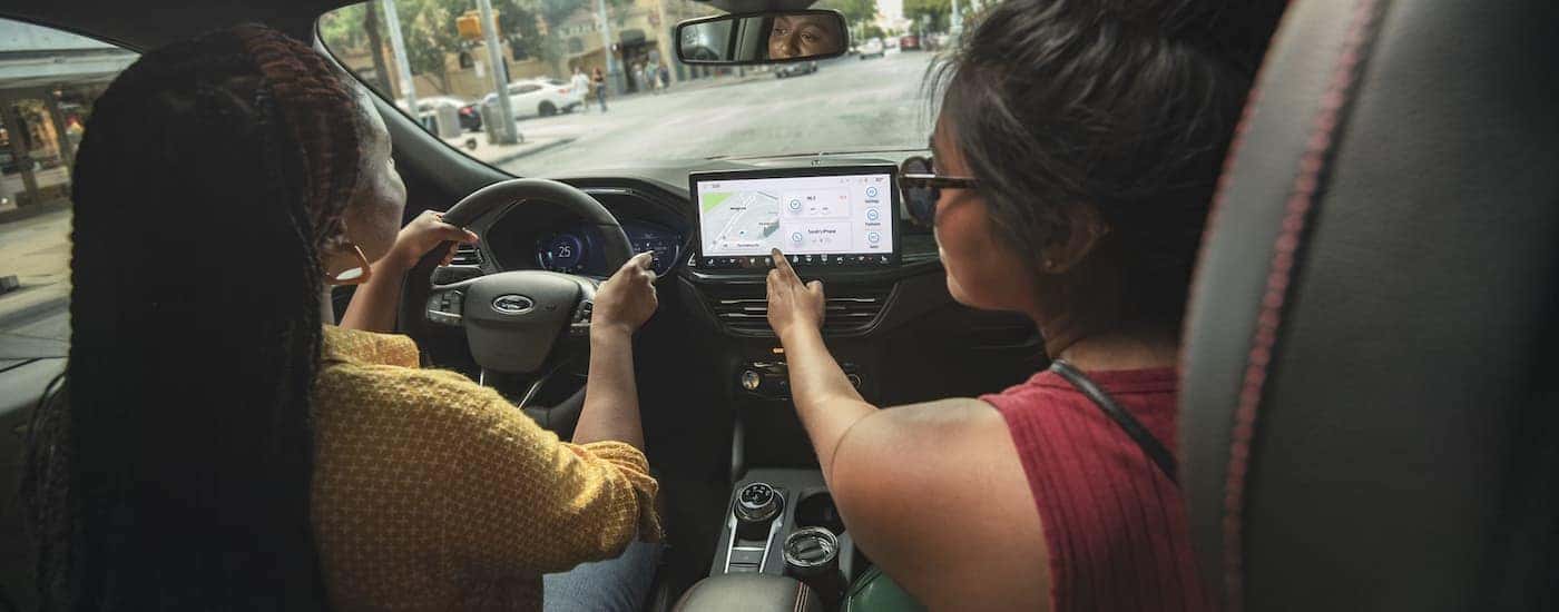 Two friends are shown driving in a 2024 Ford Escape on a city street.