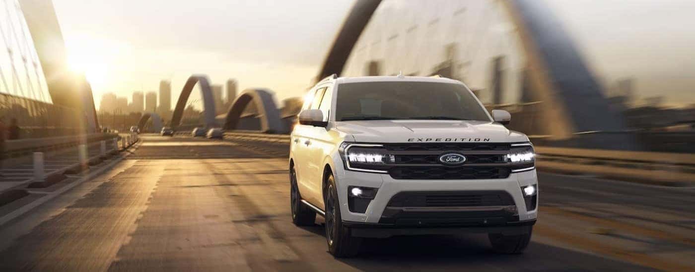 A white 2024 Ford Expedition is shown driving on a bridge.
