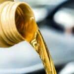 Oil is shown being poured from a container at a Ford service center.