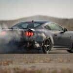 A black 2024 Ford Mustang Dark Horse is shown performing a burnout.