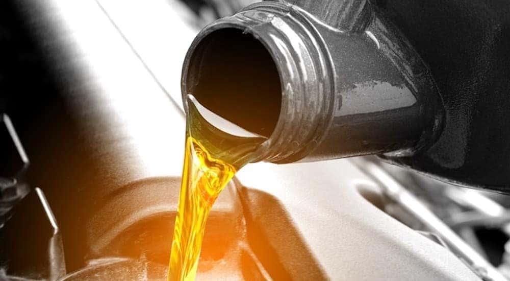 A close-up of oil being poured into an engine is shown.
