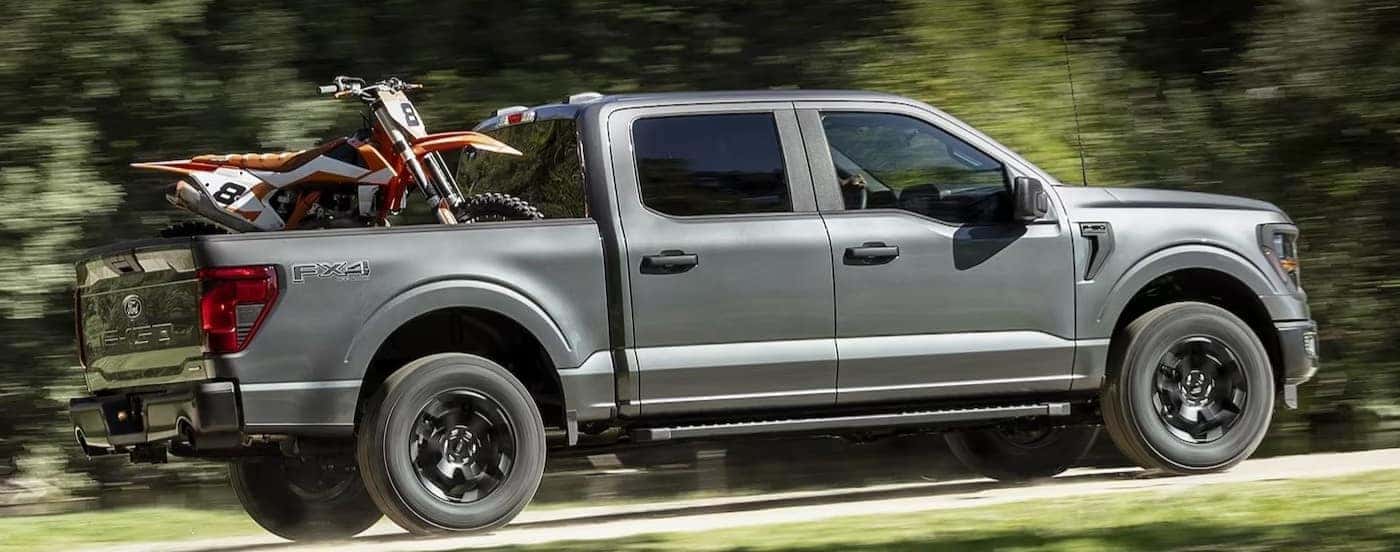 A gray 2024 Ford F-150 is shown driving off-road.