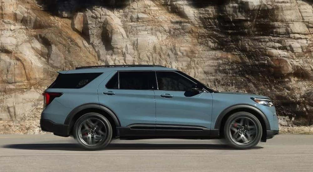 A blue 2025 Ford Explorer is shown driving on a highway.