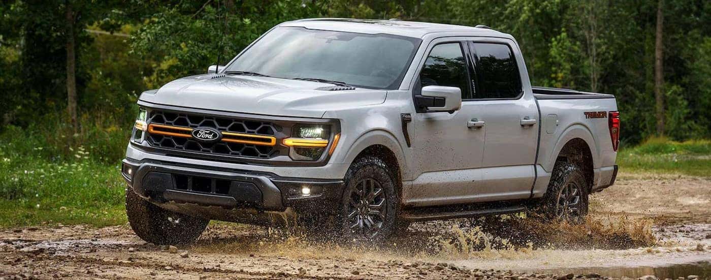 A white 2024 Ford F-150 Tremor is shown driving on mud.
