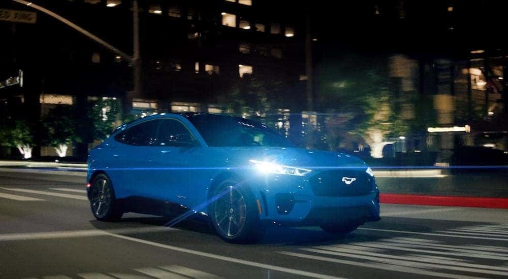 A blue 2025 Ford Mustang Mach-E GT is shown from the front at an angle after leaving a dealer that has electric vehicles for sale.