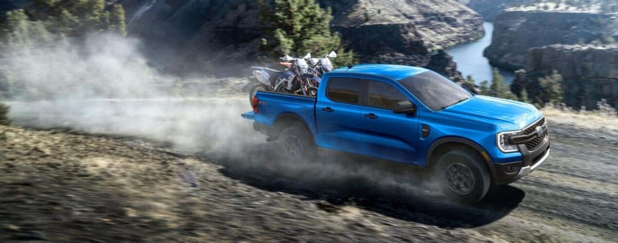 A blue 2025 Ford Ranger XLT is shown kicking up dust on a trail.