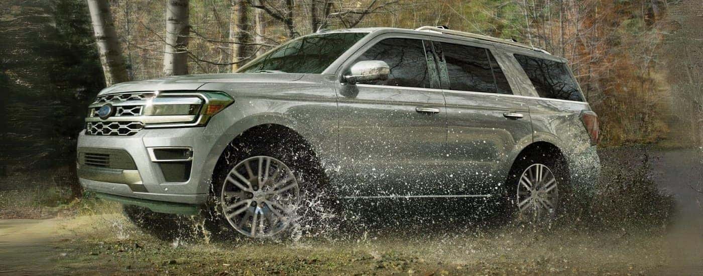 A silver 2023 Ford Expedition for sale is shown kicking up water off-road.