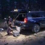 A dark blue 2025 Ford Expedition Platinum MAX parked at a campsite at night.
