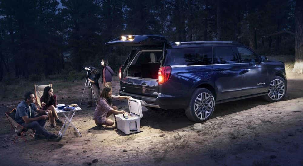 A dark blue 2025 Ford Expedition Platinum MAX parked at a campsite at night.