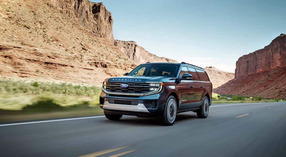 A black 2025 Ford Expedition for sale driving past cliffs.