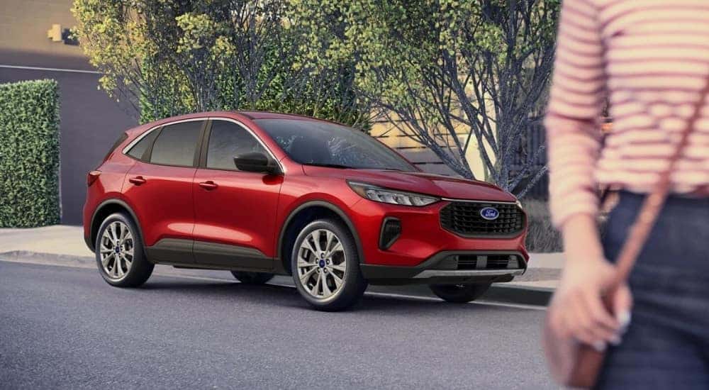 A person is walking past a red 2025 Ford Escape Active.