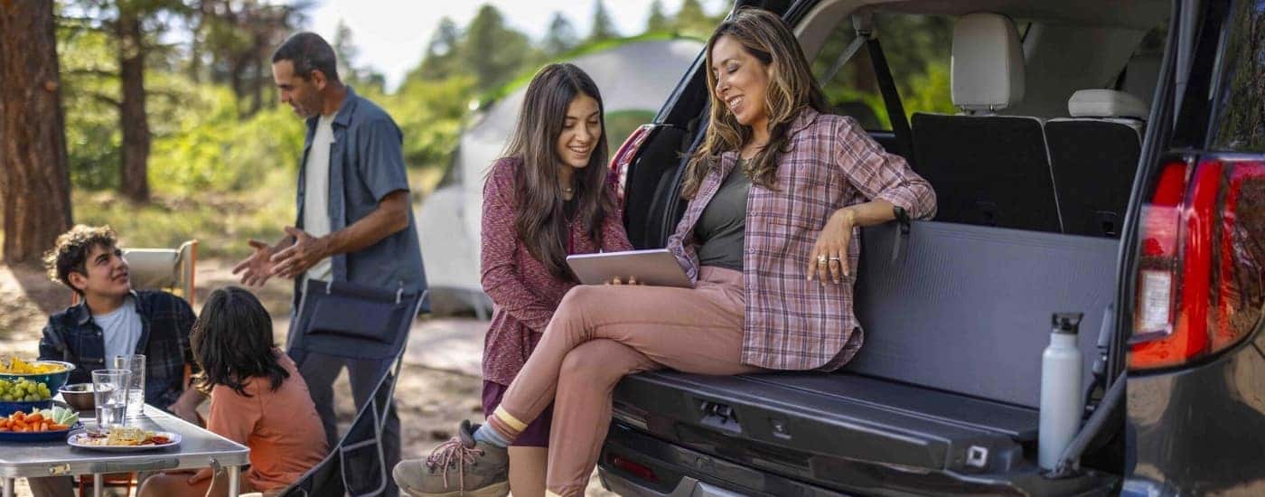 People using a tablet in the cargo area of a black 2025 Ford Expedition.