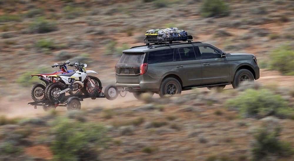 A green 2025 Ford Expedition Tremor towing a trailer off-road.