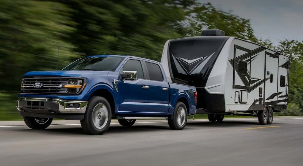 A blue 2025 Ford F-150 for sale near Roswell towing a trailer.
