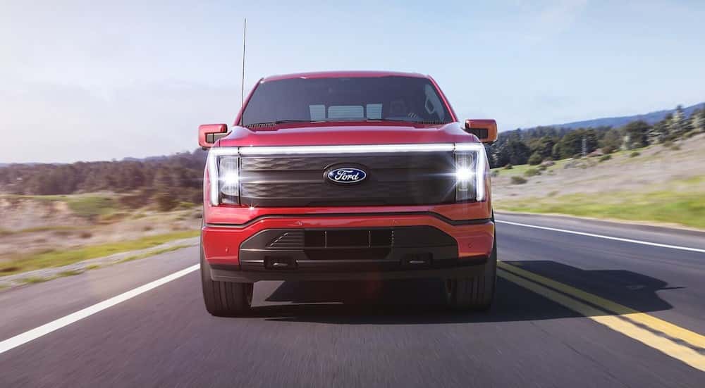 A red 2025 Ford F-150 Lightning driving on a highway.