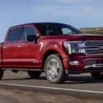 Red 2025 Ford F-150 for sale near Roswell driving down a road.