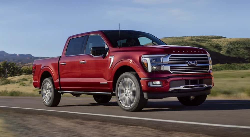 Red 2025 Ford F-150 for sale near Roswell driving down a road.