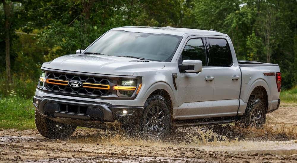 White 2025 Ford F-150 Tremor driving on mud.