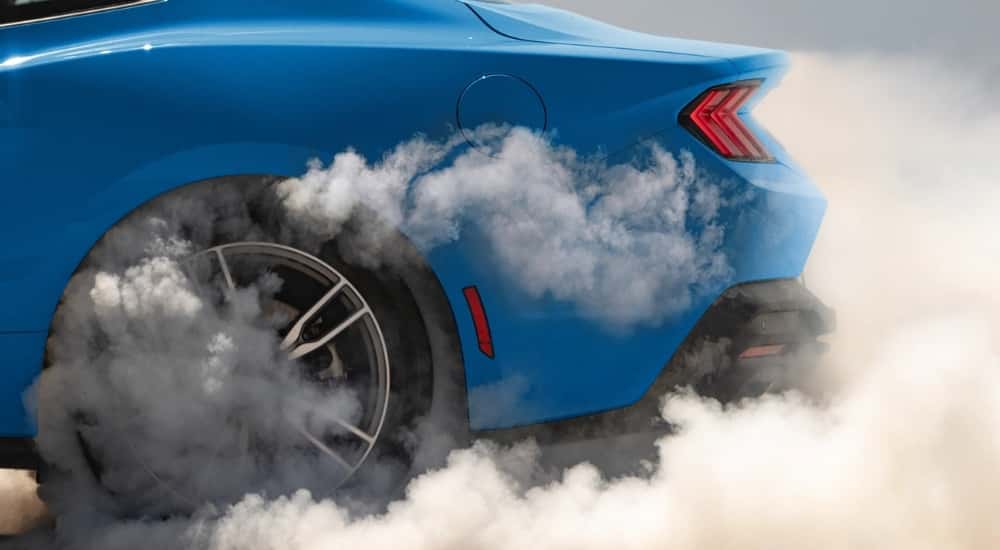 A blue 2025 Ford Mustang doing a burnout.
