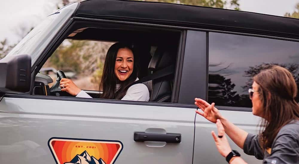 A person driving in a silver 2025 Ford Bronco.