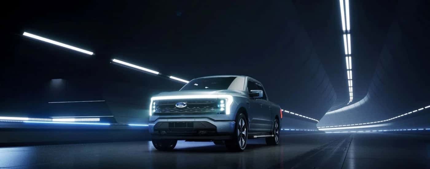 A silver 2025 Ford F-150 Lightning driving in a futuristic tunnel