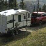 A red 2025 Ford Maverick towing a trailer.