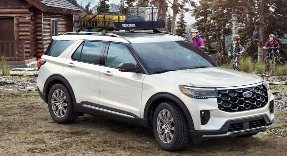 A white 2025 Ford Explorer parked near a cabin.