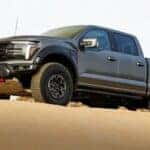 A gray 2026 Ford F-150 Raptor parked on sand.