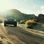 A red 2026 Ford Bronco shown off-roading in the mountains.