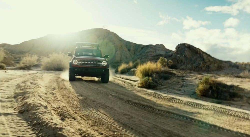 A red 2026 Ford Bronco shown off-roading in the mountains.