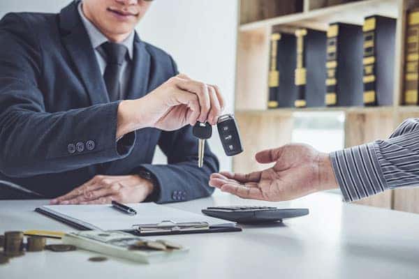 Man giving a car key to a client in an office.